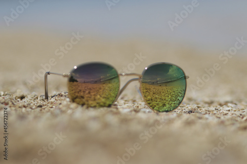 Defocused abstract background of sunglasses on sands in the beach with sky and seascape view reflection. Summer concept stock images