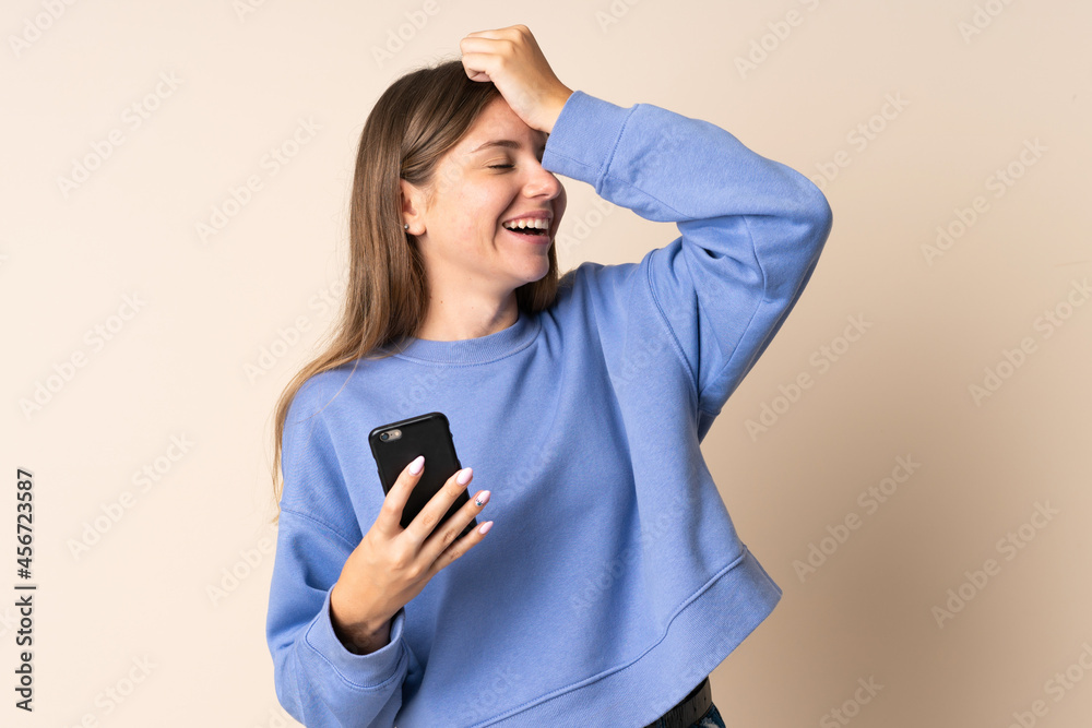 Young Lithuanian woman using mobile phone isolated on beige background has realized something and intending the solution Young Lithuanian woman using mobile phone isolated on beige background has realized something and intending the solution