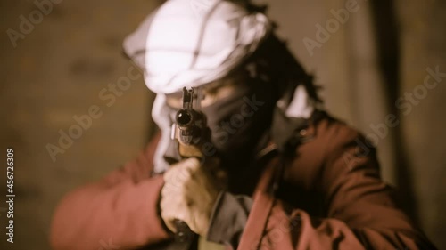 Selective focus on gun, terrorist or mafia gangster in face cover with gun looking or searching for target - concept of crime and warfare tactics. photo