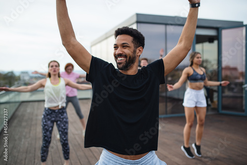 Fotografie Group of young people doing exercise outdoors on terrace, sport and healthy lifestyle concept
