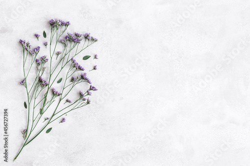 Flowers composition. Purple flowers and eucalyptus leaves on concrete gray background. Flat lay, top view