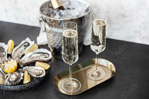 Champagne glasses with sparkling wine and bottle in bucket near oysters