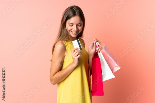 Young Lithuanian woman isolated on pink background holding shopping bags and a credit card