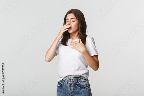 Young woman with allergy sneezing. Girl feeling sick having runny nose