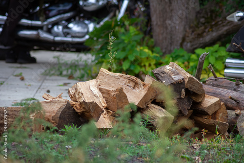 Stack of chopped firewood. There is a motorcycle in the background.