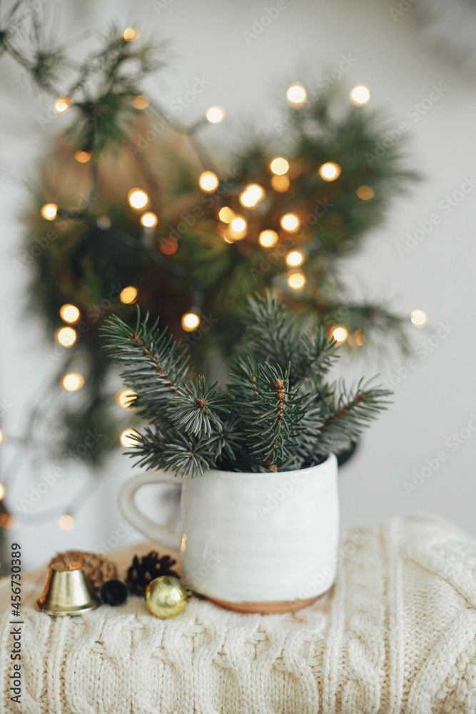 Magic winter time. Stylish modern cup with fir branches on cozy sweater with ornaments on background of warm lights and sweden star in festive scandinavian room. Atmospheric hygge home. Magic winter time. Stylish modern cup with fir branches on cozy sweater with ornaments on background of warm lights and sweden star in festive scandinavian room. Atmospheric hygge home.