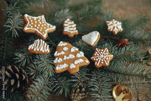 Christmas gingerbread cookies on fir branches and pine cones on rustic wooden table. Atmospheric winter image. Seasons greeting. Delicious homemade cookies. Happy Holidays