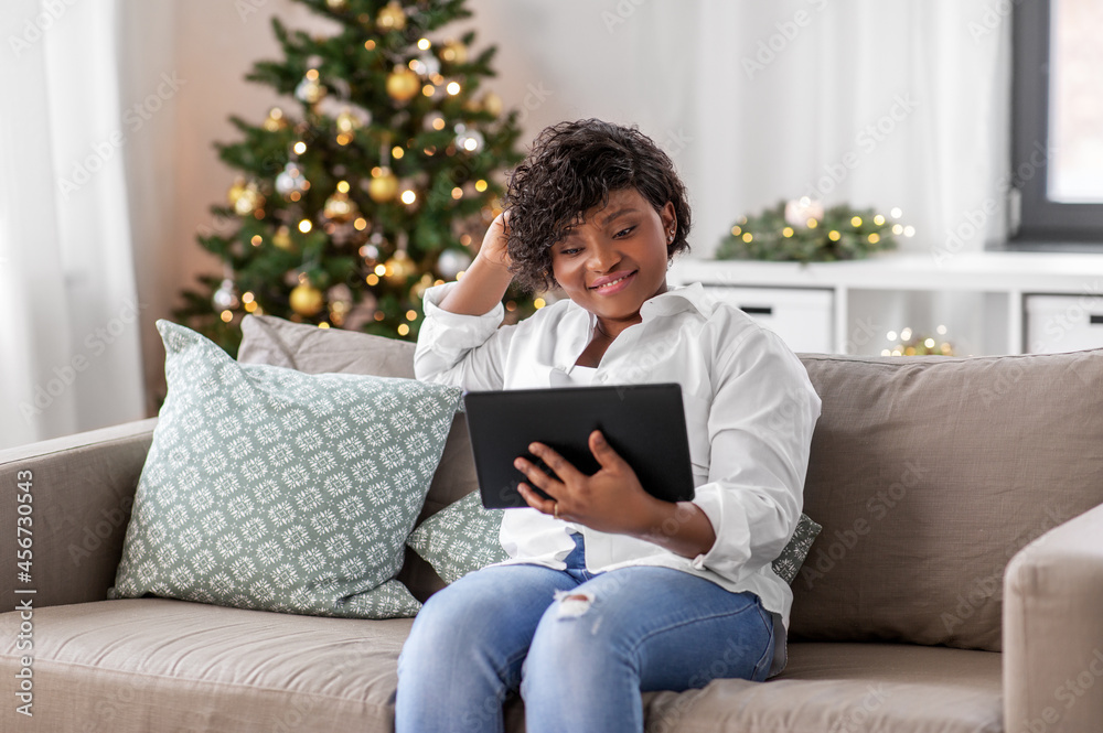 technology, people and winter holidays concept - smiling african american woman with tablet pc computer on christmas at home technology, people and winter holidays concept - smiling african american woman with tablet pc computer on christmas at home