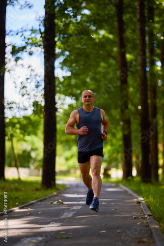 Man running in nature through the park, sports in the city.