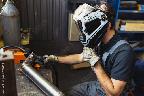 Cropped image of male auto mechanic in dungarees with work tools working at car service station, indoors. Concept of labor, occupation, business, caree, job