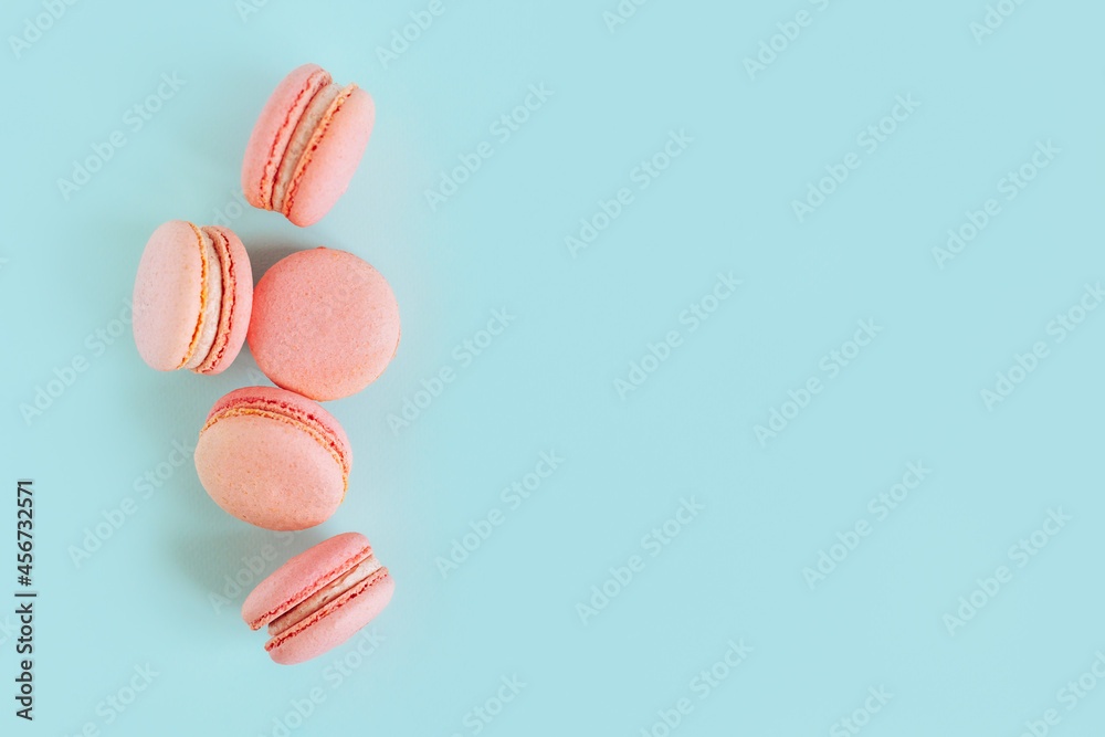 Obraz premium Tasty french pink macarons on a blue pastel background.