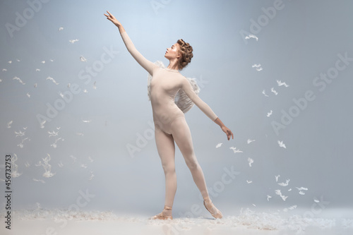 Young and graceful ballet dancer  ballerina dancing isolated on white gray studio background. Art  motion  action  flexibility  inspiration concept.