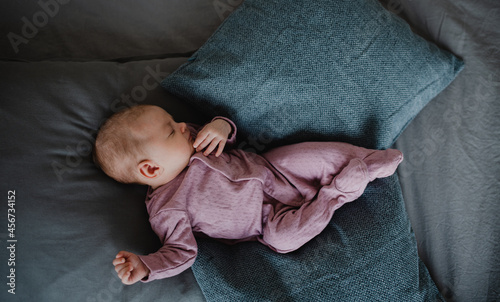 Top view of newborn baby girl, sleeping an lying on sofa indoors at home.