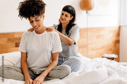 Caring young woman massaging her girlfriend at home photo