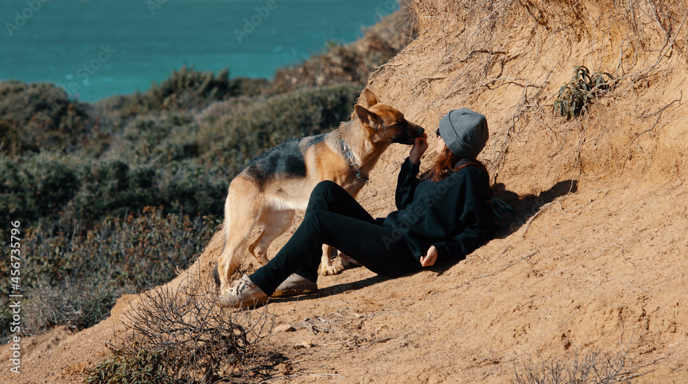 Woman offering her dog friend a treat. German Shepherd dog enjoying communication with her owner while resting from training outdoors