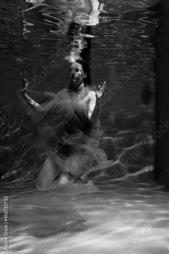 Black and white photographs where a beautiful girl poses in the water. She looks like a mythical mermaid