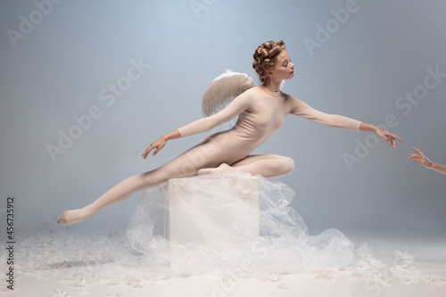 Young and graceful ballet dancer, ballerina dancing isolated on white gray studio background. Art, motion, action, flexibility, inspiration concept. photo