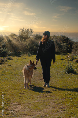 Trendy young woman walking her dog at sunset © Casther
