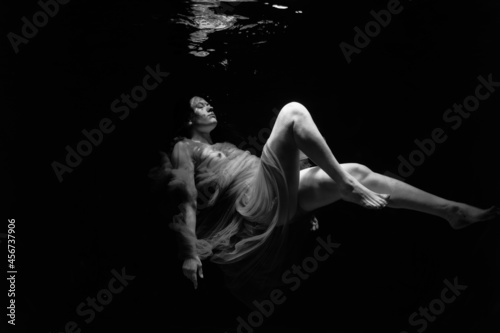 Black and white photographs where a beautiful girl poses in the water. She looks like a mythical mermaid