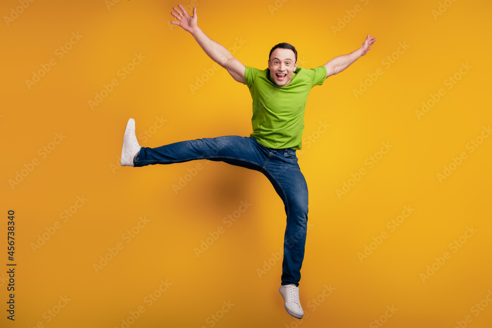 Portrait of funky dreamy casual cheerful guy jump excited mood on yellow wall