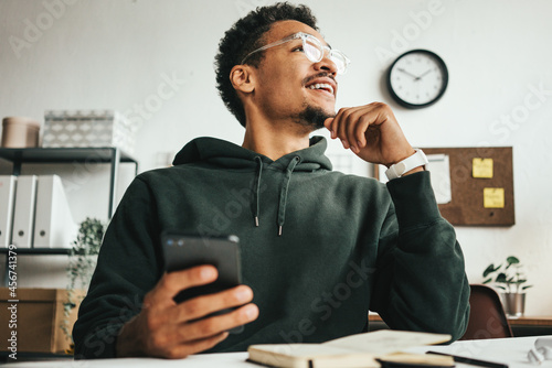 Investing in stock exchange market. Smiling black casual man working using mobile phone app