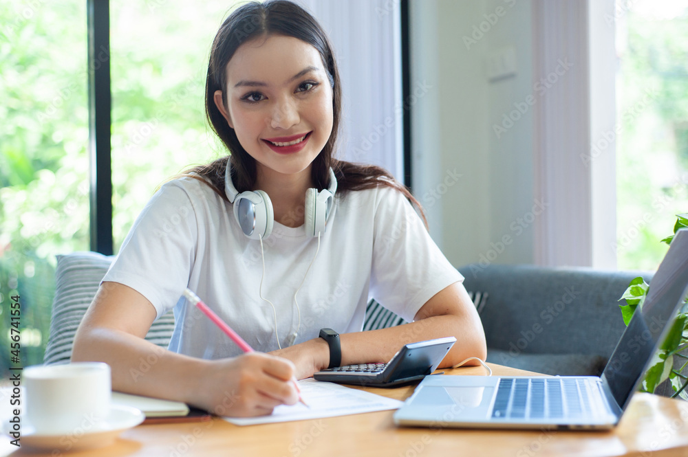 A female student is writing and studying online via the Internet at home. The concept of working at home, meetings, webinars via the Internet. A female student is writing and studying online via the Internet at home. The concept of working at home, meetings, webinars via the Internet.