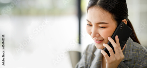 Asian young Businesswoman talking on cell phone in office hallway,blur background.