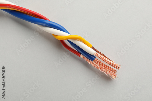 Many twisted electrical wires on light background, closeup
