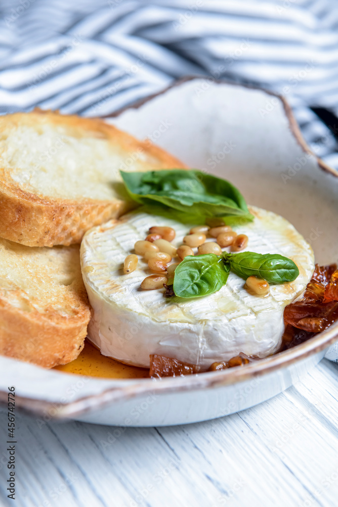 Baked camembert with sauce and toast served in a white bowl. Delicious dinner idea