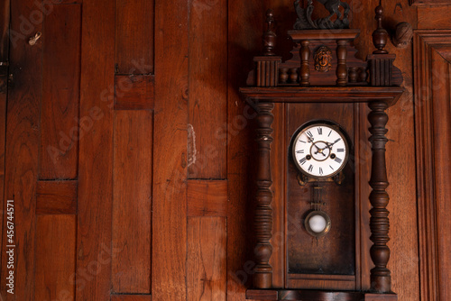 antique pendulum clock hanging on the wooden wall