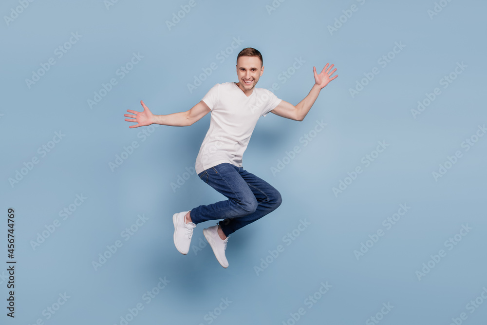 Full body profile side photo of cheerful excited man jumping have fun isolated over blue color background