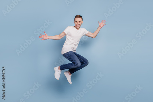 Full body profile side photo of cheerful excited man jumping have fun isolated over blue color background
