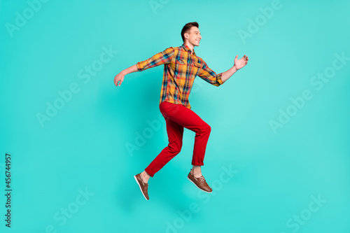 Full size profile photo of funky brunet young guy jump wear shirt turquoise sneakers isolated on teal background