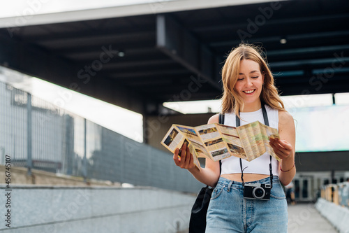 Young caucasian woman traveller holding tourist map smiling discovering and sightseeing