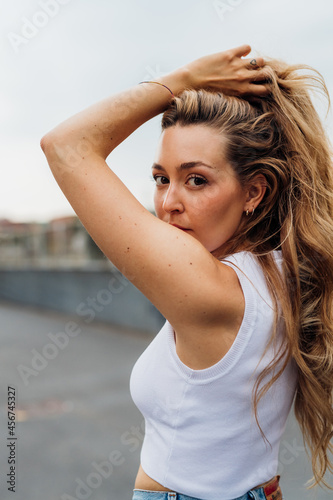 Portrait of young serious and dreamy woman outdoor looking camera posing touching hair