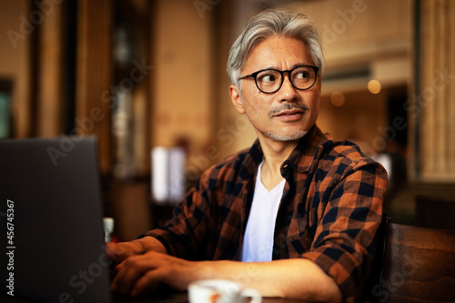 Businessman working on laptop in cafe. Handsome senior man enjoying in fresh coffee. photo