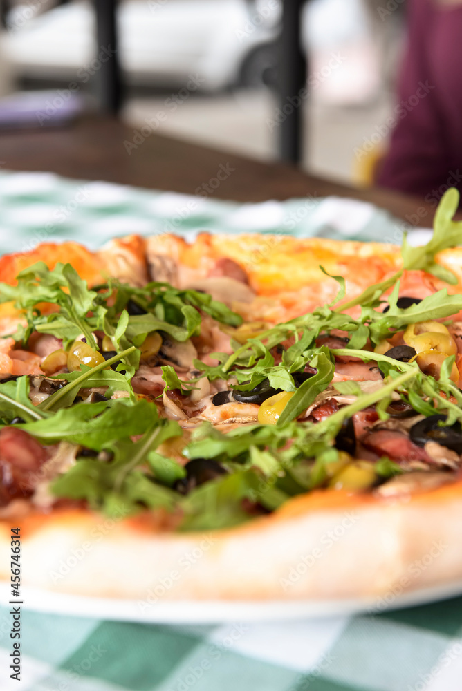 Delicious Italian pizza served on wooden table with green plaid tablecloth, traditional recipe.