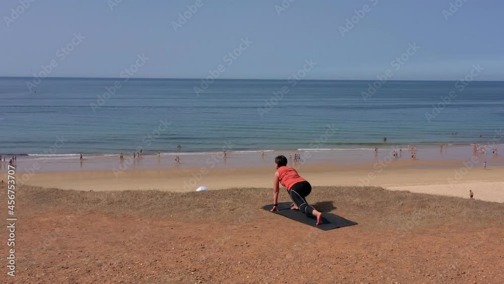 A middle-aged woman on the ocean shore goes in for sports, gymnastics. Exercise lunges. On the seashore with a view of the beach. A middle-aged woman on the ocean shore goes in for sports, gymnastics. Exercise lunges. On the seashore with a view of the beach.