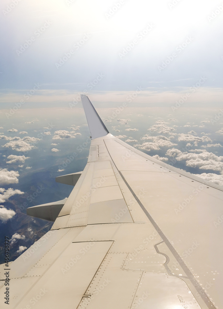 Ala de avión volando en el cielo con mar de nubes y espacio para texto.