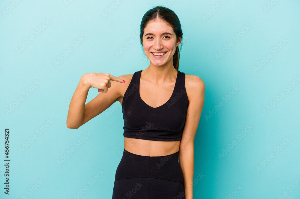 Young sporty caucasian woman isolated on blue background person pointing by hand to a shirt copy space, proud and confident Young sporty caucasian woman isolated on blue background person pointing by hand to a shirt copy space, proud and confident