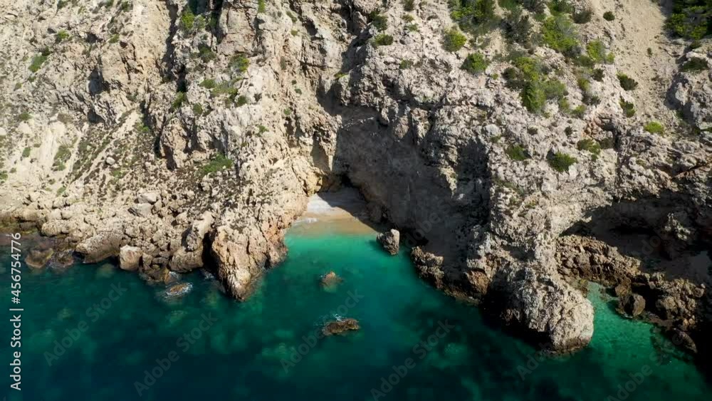 The beautiful beach front of the Island of Ibiza in Spain, taken with a drone in the summer time showing a small private secluded paradise style beach in-between the cliff front The beautiful beach front of the Island of Ibiza in Spain, taken with a drone in the summer time showing a small private secluded paradise style beach in-between the cliff front