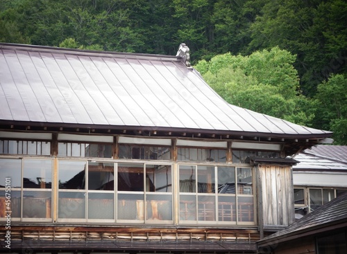 Traditional Japanese style old house building sharp wooden structure roof and rusty window frame in forest photo