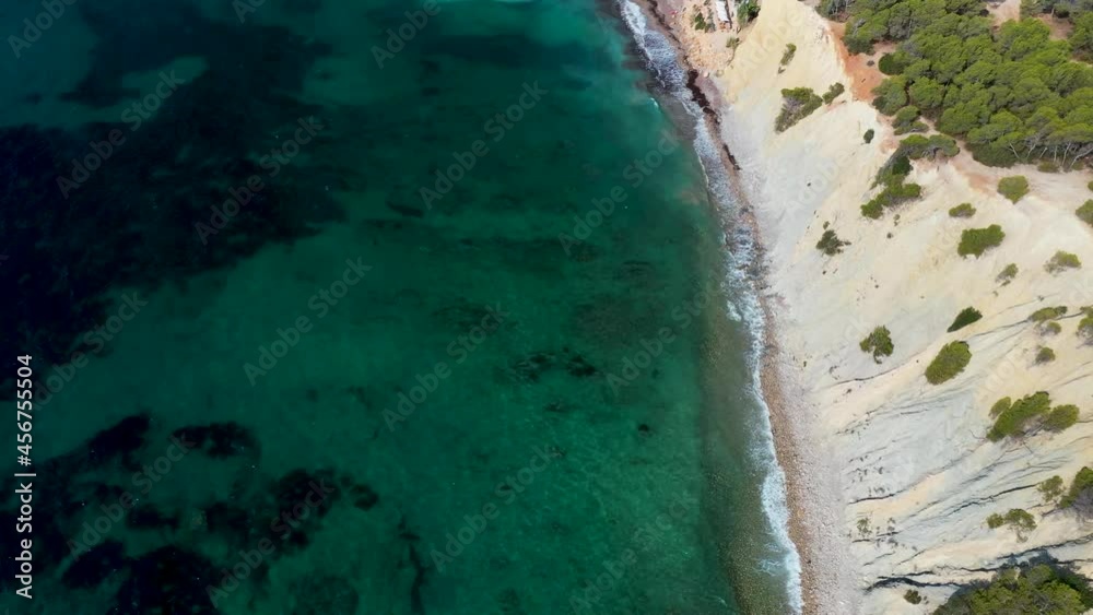 The beautiful beach front of the Island of Ibiza in Spain, taken with a drone in the summer time showing the cliffs and ocean on the Island The beautiful beach front of the Island of Ibiza in Spain, taken with a drone in the summer time showing the cliffs and ocean on the Island
