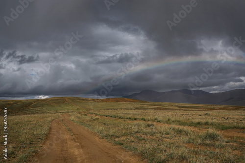 road dirt steppe rainbow mountains clouds