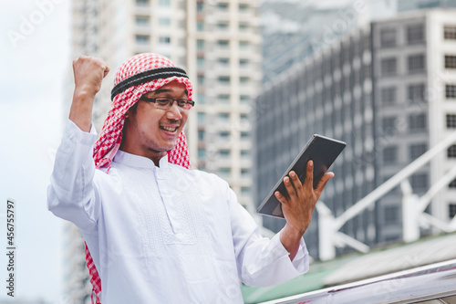 Islamic man using smartphones app organize schedule agenda  focus on hands holding smartphone muslim modern uae city. Arab men wear hijab and muslim formal dress sending text sms online lifestyle photo