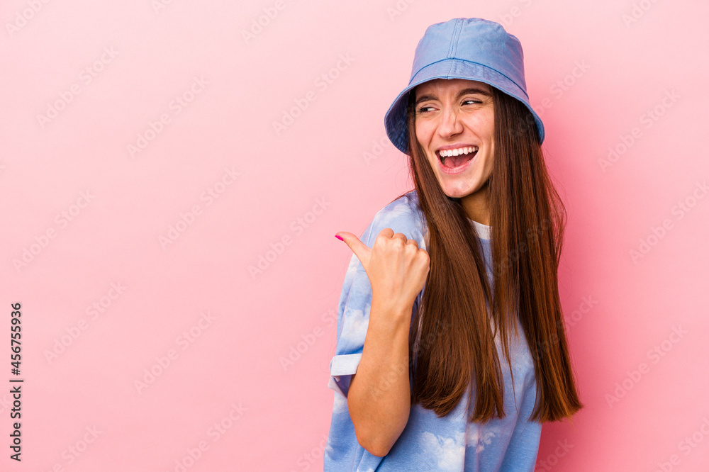 Young caucasian woman isolated on pink background points with thumb finger away, laughing and carefree. Young caucasian woman isolated on pink background points with thumb finger away, laughing and carefree.