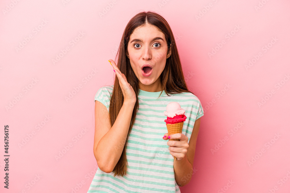 Young caucasian woman holding an ice cream isolated on pink background surprised and shocked. Young caucasian woman holding an ice cream isolated on pink background surprised and shocked.