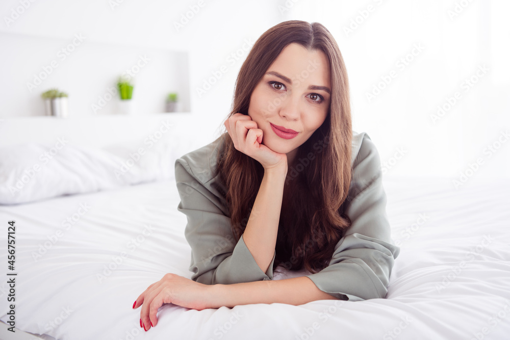 Portrait of attractive cheerful girl lying on cosy soft bed staying safe at home house light white interior