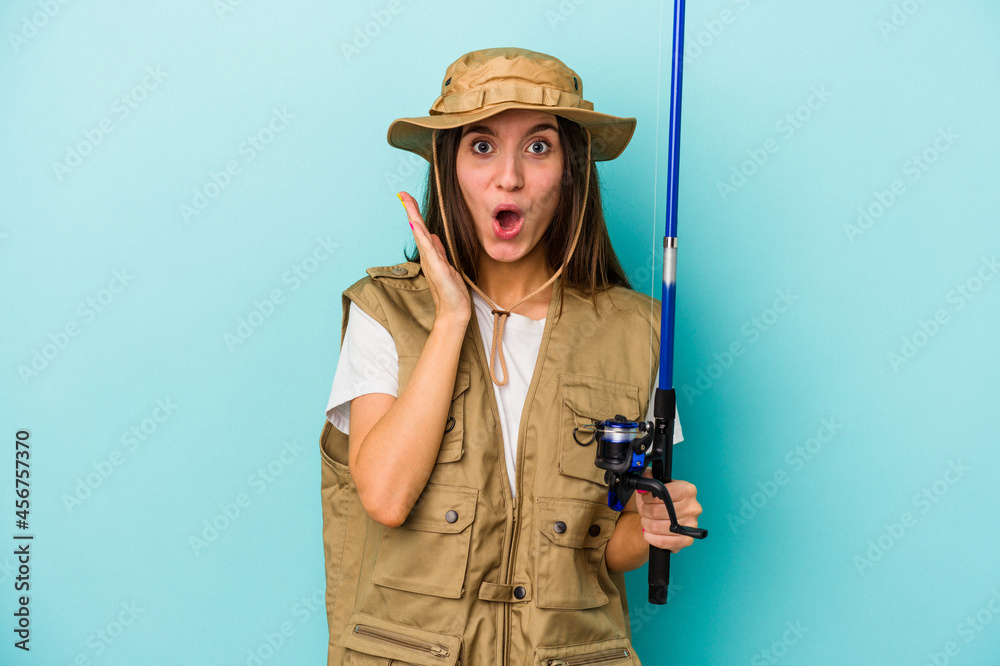 Young caucasian fisherwoman isolated on blue background surprised and shocked. Young caucasian fisherwoman isolated on blue background surprised and shocked.