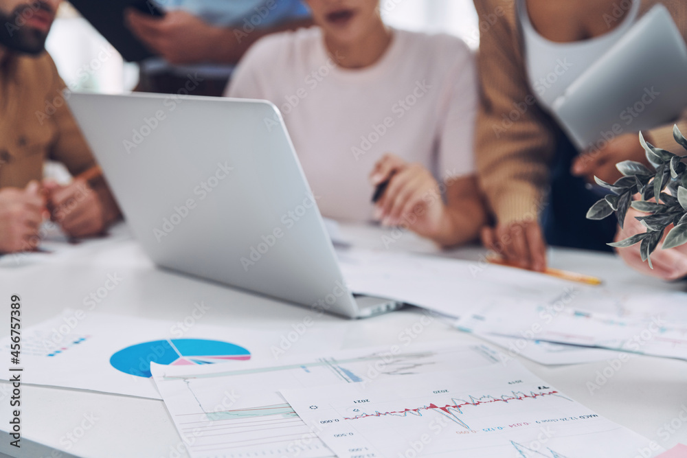 Close-up of modern people in smart casual analyzing data while having meeting in office Close-up of modern people in smart casual analyzing data while having meeting in office